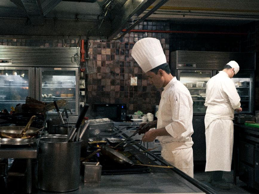 Authentic restaurant culinary team preparing smash burgers in professional kitchen